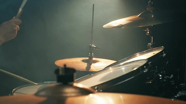 Young female drummer plays drums in a room full of smoke. Music or song recording, creation. Music band repetition