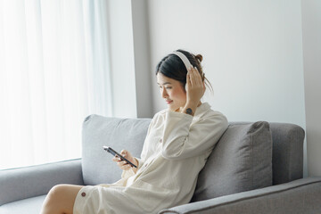 Happy Young Asian woman wearing headphone  listening to music relax in living room