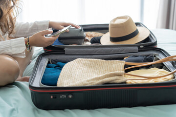 Woman packing suitcase on bed for a new journey packing list for travel planning preparing vacation...