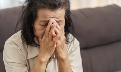 Sad middle age Asian woman touching forehead having headache suffering from migraine. mature asian woman feeling sick or depression.