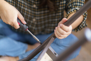 Asian Woman self repairs furniture renovation using equipment to diy repairing furniture sitting on the floor at home