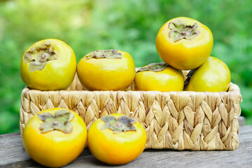 Ripe yellow sweet persimmon fruits in wicker basket. Diospyros family plants.  Concept, Agriculture crops. Seasonal fruit. Healthy eating.     