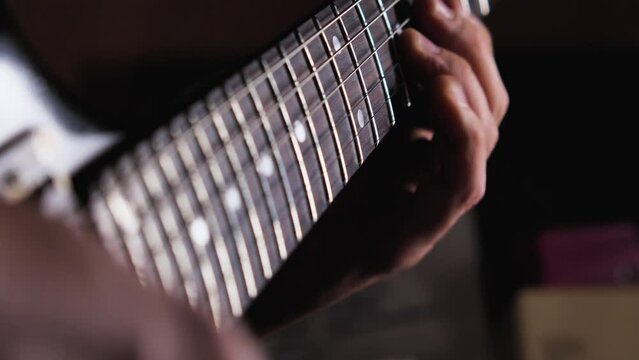 Close-up of playing solo on electric guitar. The fingers of the left hand clamp and tighten the strings on the fingerboard. Rehearsal of the programme in the studio before the tour