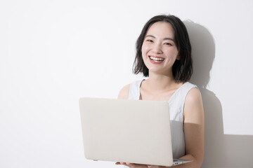 パソコンを持つカメラ目線の勉強する若い学生っぽい女性の正面