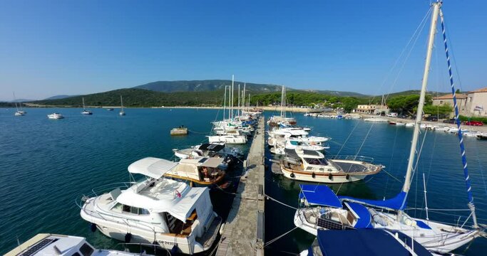 Cinematic FPV drone soars along empty dock with sailboats and yachts at pier of Osor Island Croatia
