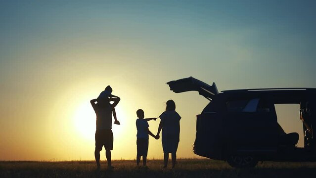family traveling by car. family watching the sunset silhouette next to the car in the park. happy family kid dream concept. people in the park. lifestyle family car camping resting in nature