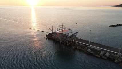 Aerial landscape view over a trabucco, traditional fishing machine, on the italian seashore, at sunset