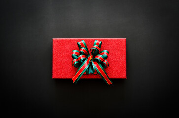 Red gift box with ribbon on black background for Boxing day and Black Friday shopping sale concept.