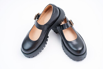 Pair of female black leather shoes on white background close-up.