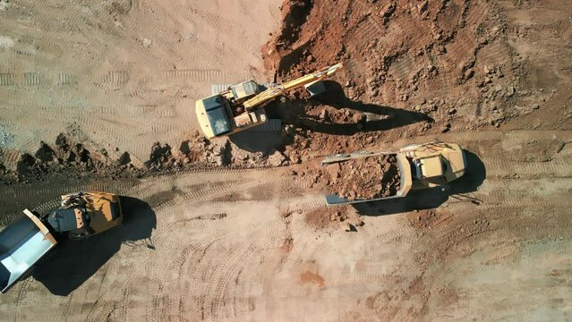 Drone top down shot of Excavator loads sand into mining truck. Mining Excavator loads sand rock into haul truck