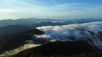 Aerial view over the mountains with sea of fog during morning sunrise in blue sky. Sea of clouds around mountain peaks at sunrise. Unseen travel in Northern Thailand