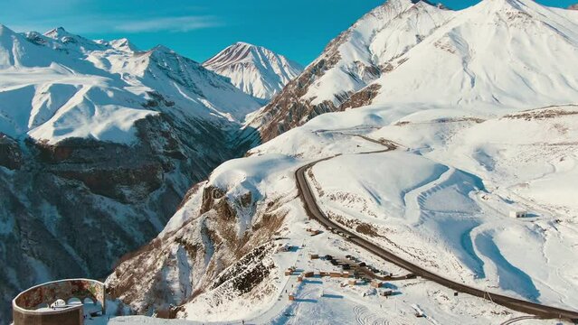 Epic Aerial shot of snowy mountains with snow and a road with cars. Sunny weather weather. Daytime