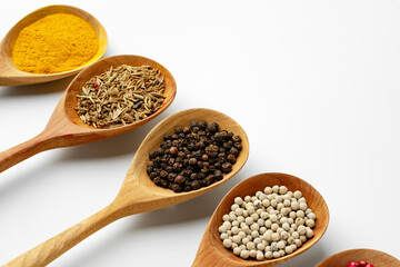 Wooden spoons with various spices isolated on white background