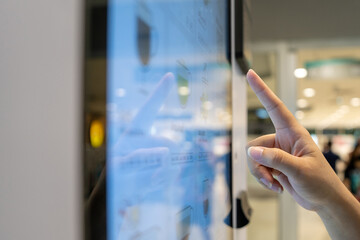Young Asian woman interacting with a screen from a coffee vending machine. - obrazy, fototapety, plakaty