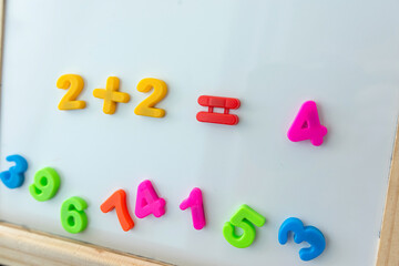 White board with magnetic numbers, primary school math. Solving examples