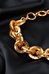 Gold chain on black silk fabric background
