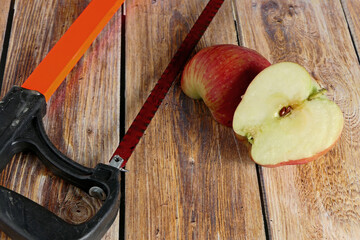 red apples and an old saw on wooden background
