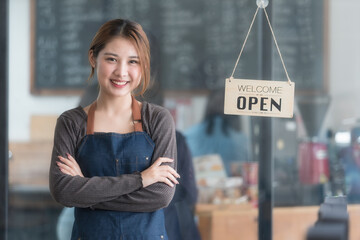 Asian female barista wearing a jean apron crossed her arms, cafe service concept, owner business start-up.