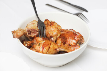 Chicken legs recipe. Cheap dinner idea background. Crunchy chicken skin. Lunch meat snack. Roasted chicken leg in bowl. White plate and silver fork. Fried meat. Grilled chicken. White table cloth.