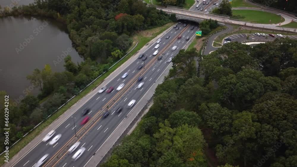 Poster an aerial time-lapse of a highway on a cloudy day showing motion blur of the vehicles passing by. th