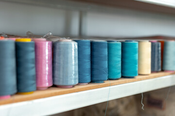 Row of multicolored thread spools at sewing factory