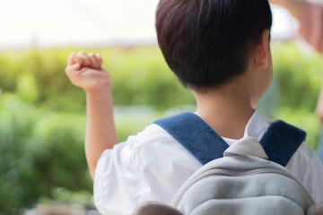 Cute little adorable toddler Asian boy on his first day going to playschool on park background.