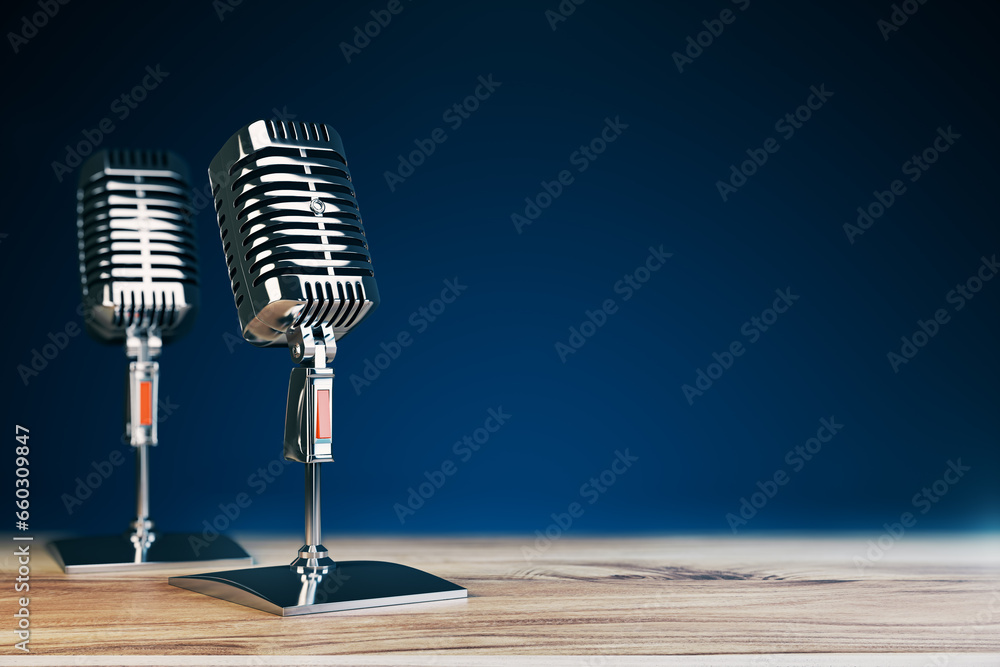 Poster close up of two steel vintage singing vocal microphones on wooden surface and blue background with m