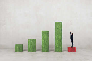 Businessman pointing up on low chart bar looking at top. Success and career growth concept. Concrete wall background.