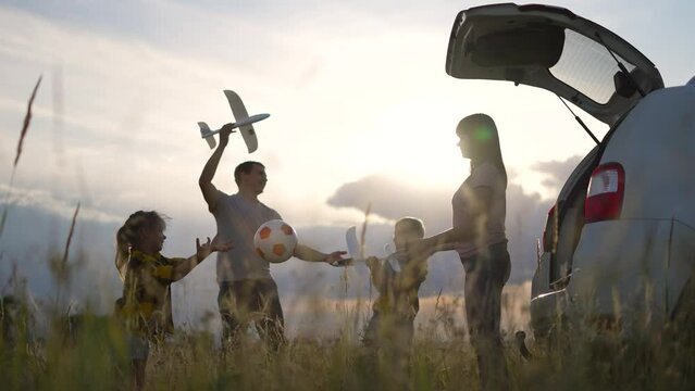 Happy family concept. Silhouette of family in car. People travel by car. Picnic in nature. Family game by the car. Happy road trip weekend. Sunset in nature. Picnic by car. Summer travel in nature