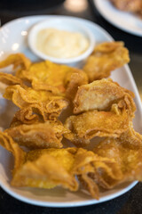 Fried wonton with sauce on a white dish. Close up