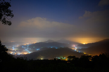 A colourful night view of illuminated villages in a valley surrounded by clouds. Night view of Jinlong Mountain in Yuchi Township, Nantou County. Taiwan