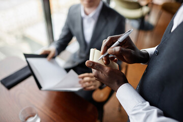Close up of male waiter holding notepad and taking order from guests in luxury restaurant, copy space