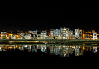 Fototapeta na wymiar Night view of the Bouzas neighborhood in the city of Vigo. The buildings are reflected in the sea. Rías Baixas, Galicia, Spain.