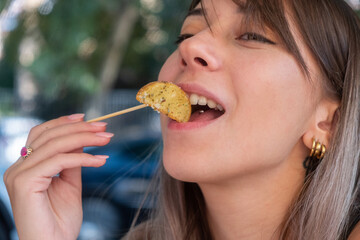 Closeup of a young woman eating baked potato outdoor