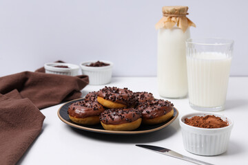 Chocolate donuts on plate, bottle and glass with milk and bowls on white background