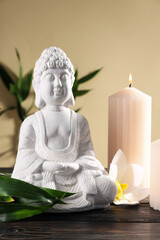 Buddha statue, bamboo, candles and flower on beige background