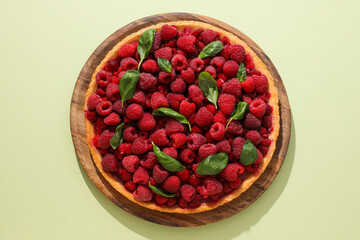 Berry pie on wooden board on light green background, top view