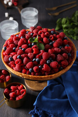 Berry pie, mint, raspberries, glasses and towel on wooden background