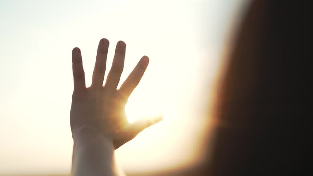 Hand of happy girl at sunset. Sunset between the hands of girl. Happy girl with long hair dreamily stretches out her hand to the sun. Child dream hand to the sun. happy family concept. Palm on the sun