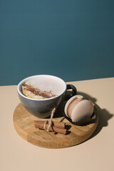 A cup of warm cocoa with a macaroon and cinnamon sticks. Warm drink for cold weather.