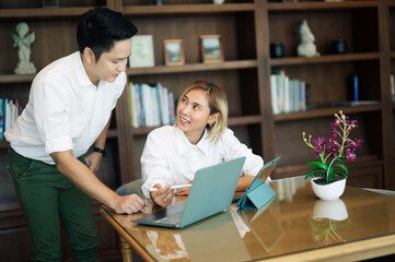Young beautiful woman look at laptop with smile and discussing something with her coworker while sit at office