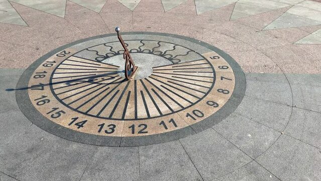 Close-up view of horizontal sundial on city square in a sunny summer day. Five o'clock. Evening high tea time. Soft focus. Slow motion video. Time theme.