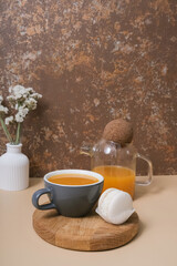 Obraz na płótnie Canvas Cup and teapot of sea buckthorn tea and macaroon. Cozy autumn winter still life