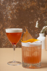 Bright alcoholic cocktails in glasses on beige brown background close up.