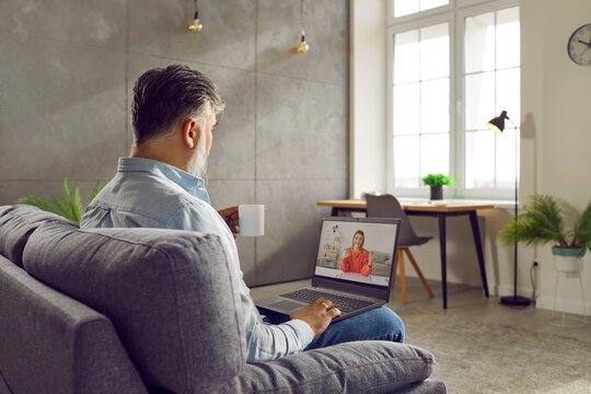 Gray Haired Bearded Businessman Talking With Young Woman Using Laptop. Side View Of Middle Aged Man Having Onine Date, Talking On Video Call With Female Partner, Coworker, Colleague From Home