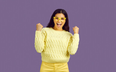 Excited Latin girl in glasses make yes hand gesture celebrate success or win. Smiling Latino woman...