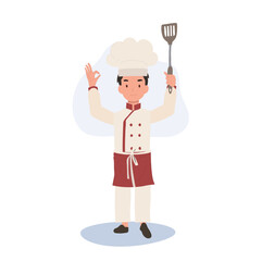 Young Chef Showing OK Sign. Happy Chef Doing OK Hand Sign and holding flipper in other hand.