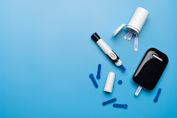 Obraz premium Diabetes awareness concept of glucose meter test strips and lancets on blue background flat lay