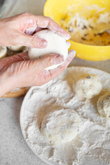 Caucasian female hands making cottage cheese pancakes with raisins cooking background