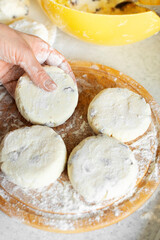 Caucasian female hands making cottage cheese pancakes with raisins cooking background